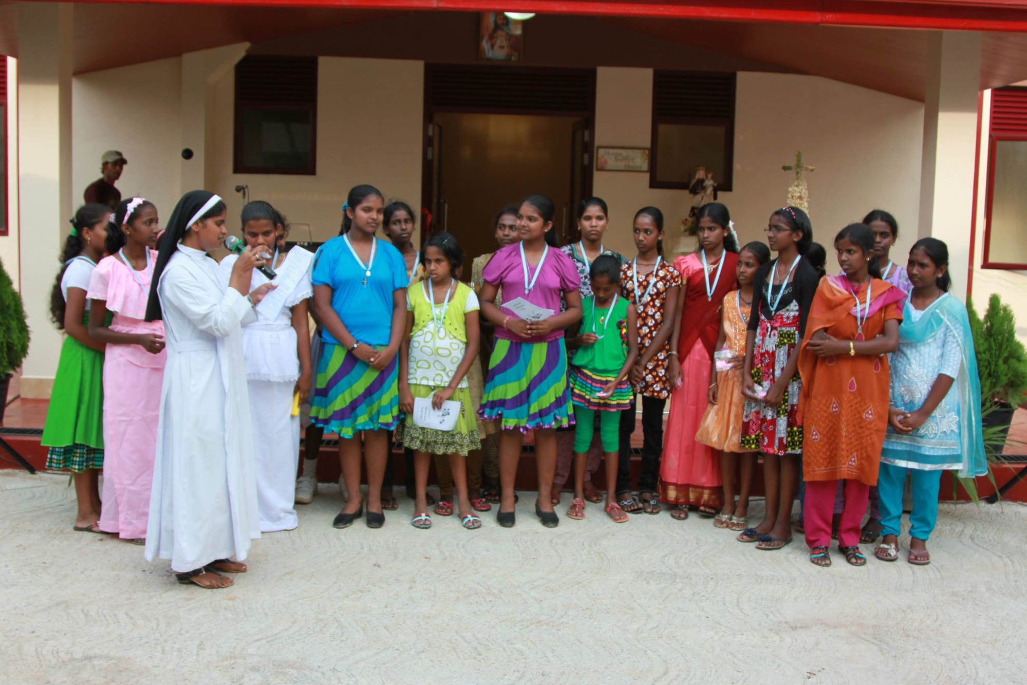 group photo of girls and nuns in front of the home